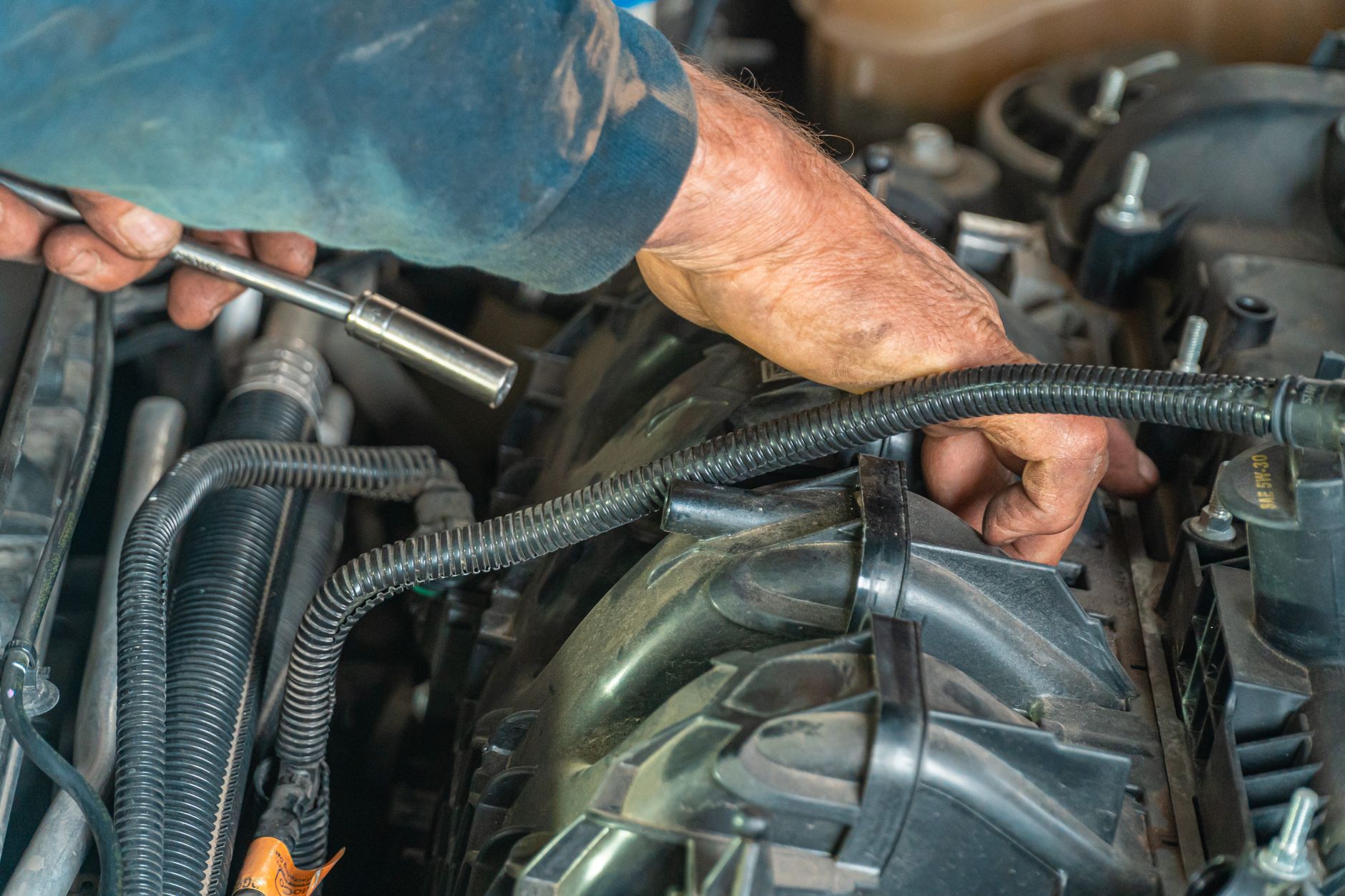 Hands working on a vehicle engine; representative auto-repair photography
