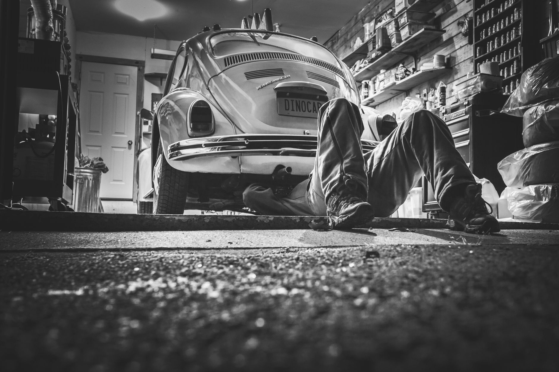 Mechanic beneath a classic car in a garage; representative photography